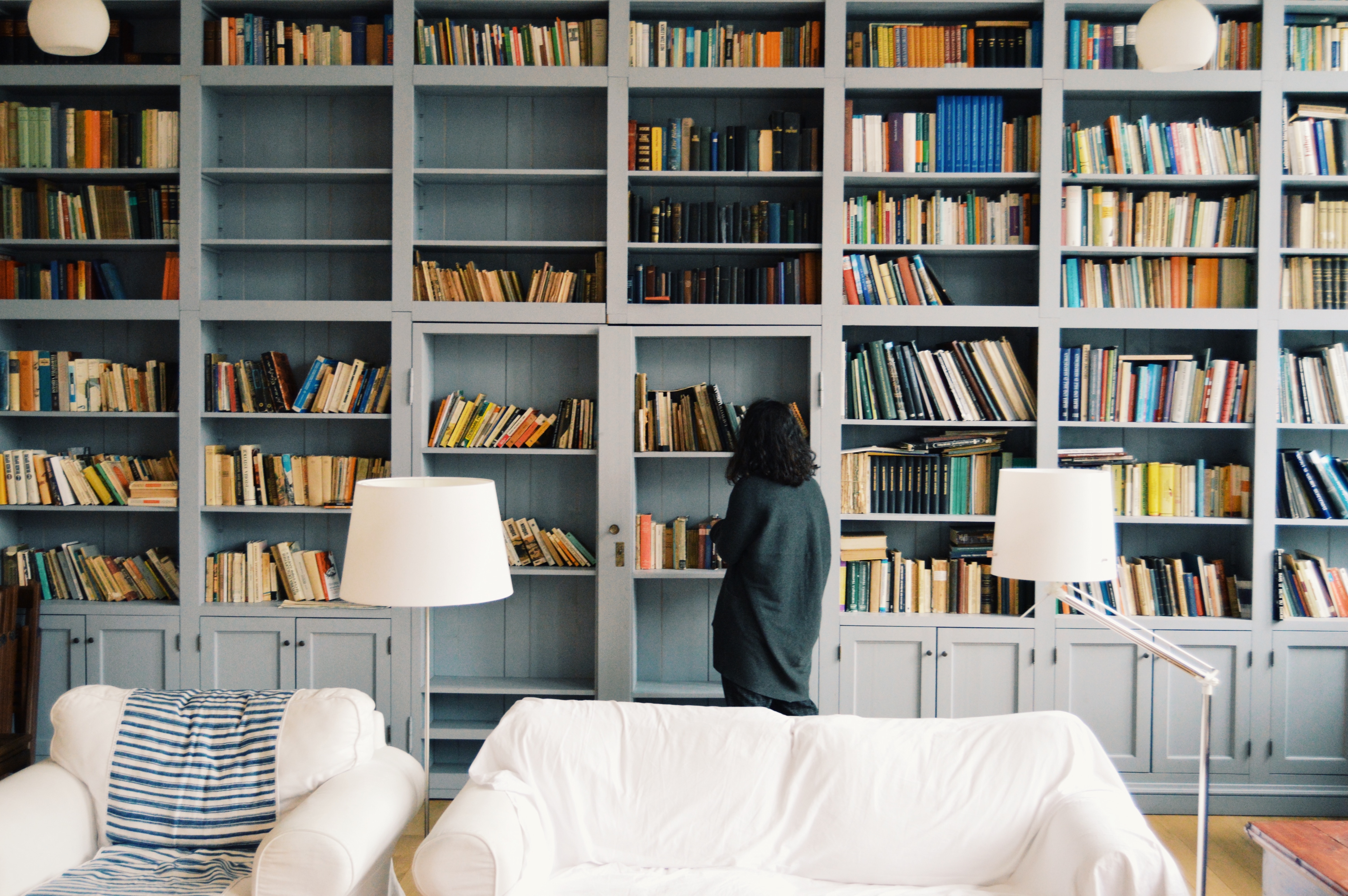 Girl standing in front of a bookshelf. There are research-proven ways to increase esl vocabulary words retention.