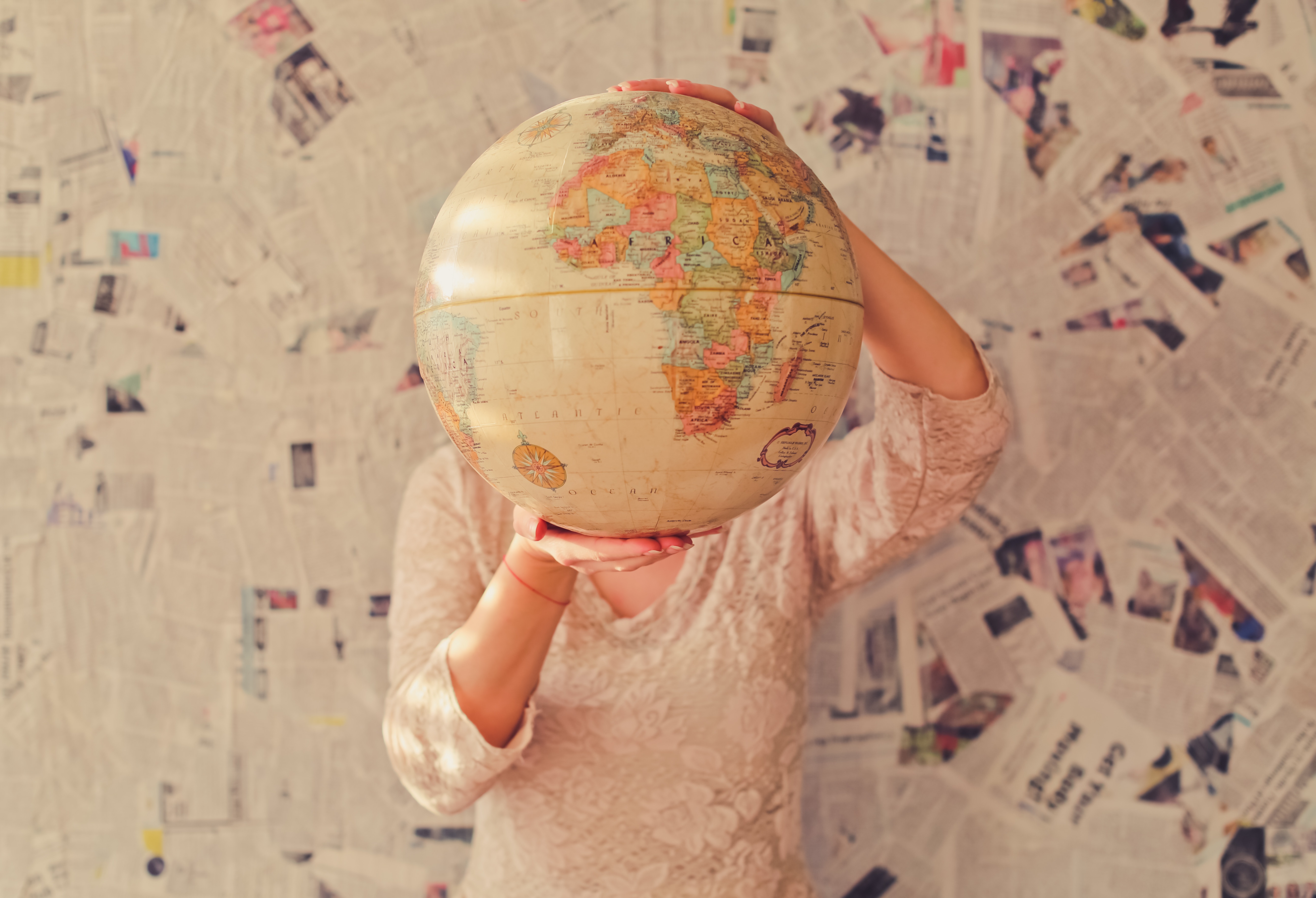 A woman holding up a globe, showing the various options of countries for teaching english abroad.